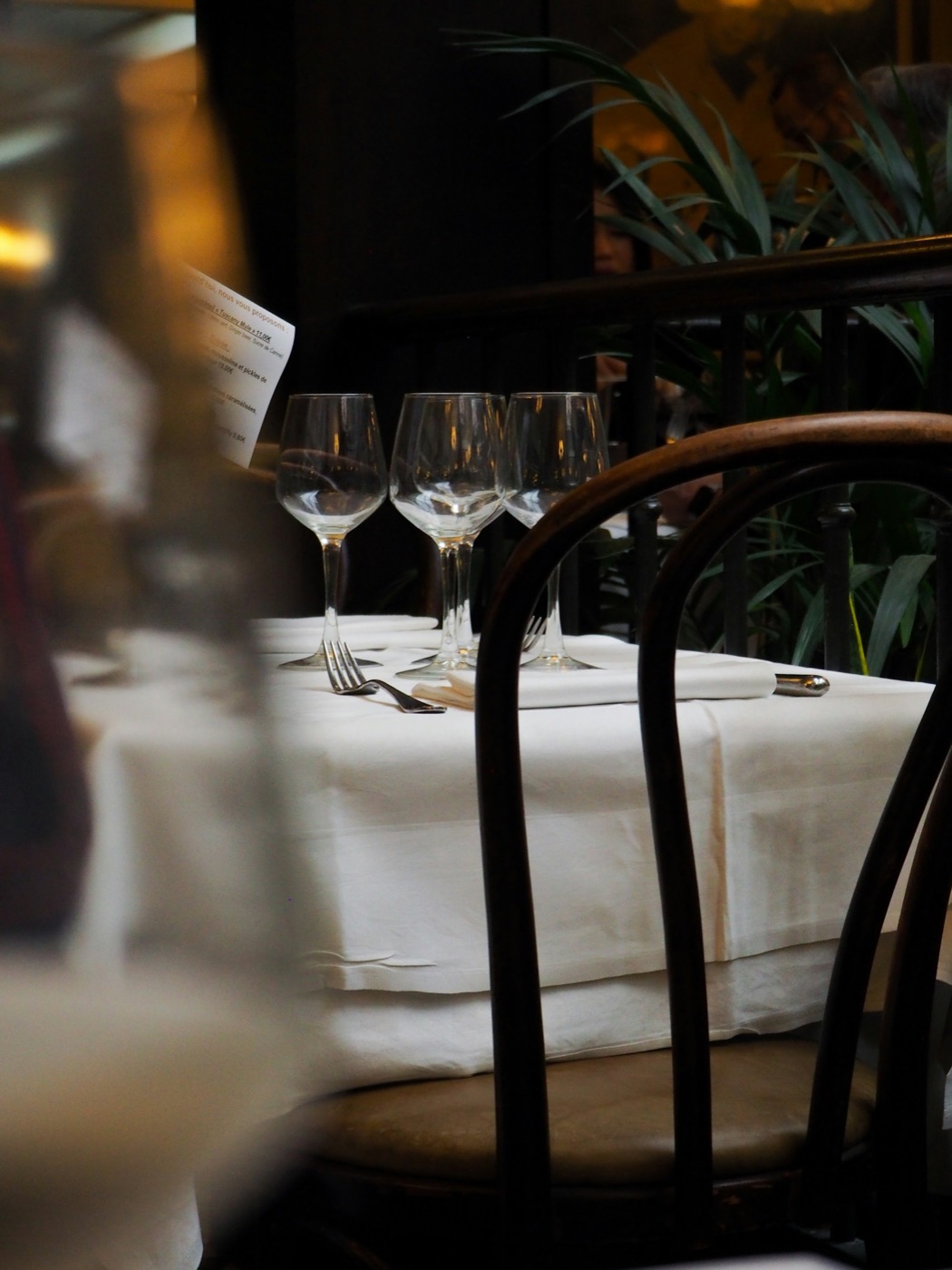 Een gedekt tafeltje in een brasserie, met wit tafelkleed en wijnglazen